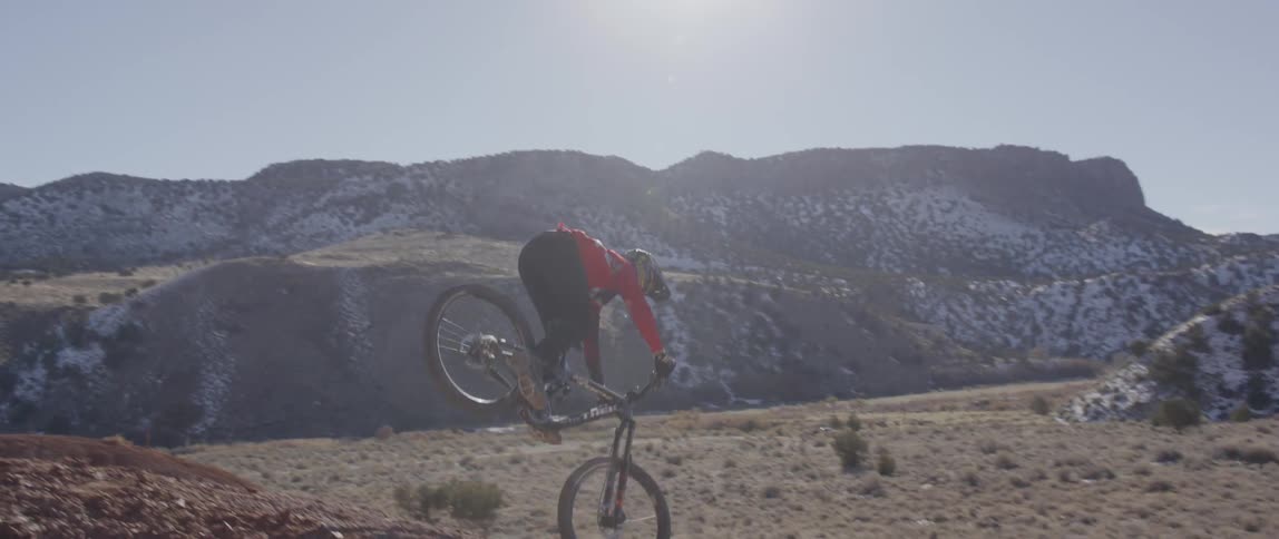 A person does bike tricks on a hill