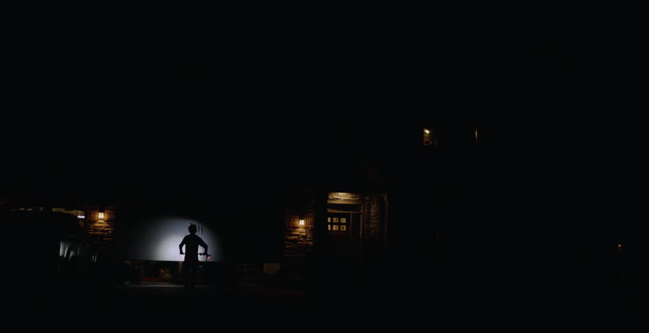 Person rides a bike with a light on it up to a garage door at night