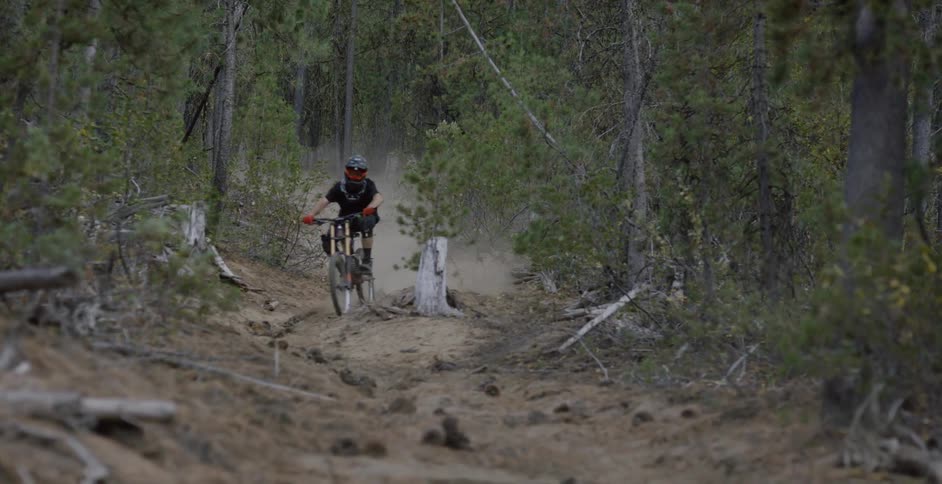 Cyclist riding down a dusty trail in the woods