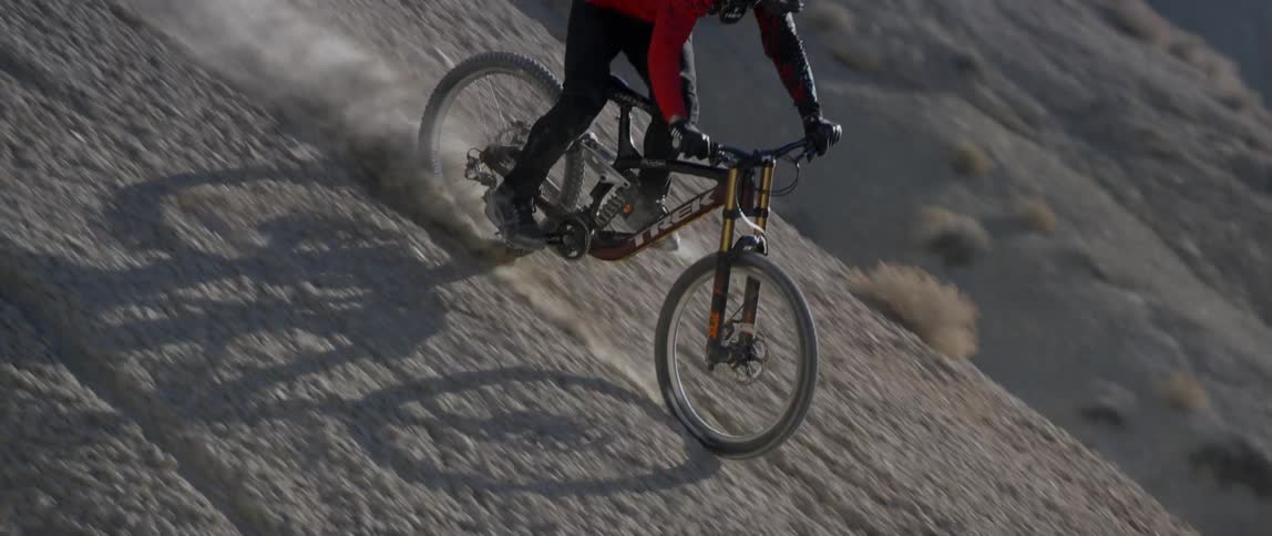 A bicyclist rides down a dirt mountainside