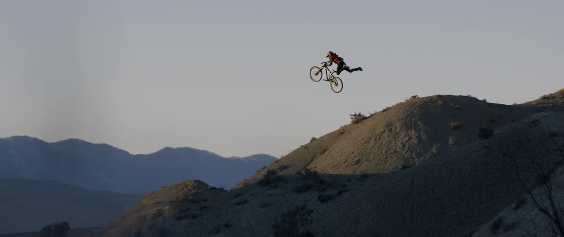 A bicyclist jumps off of a steep ramp and performs a trick