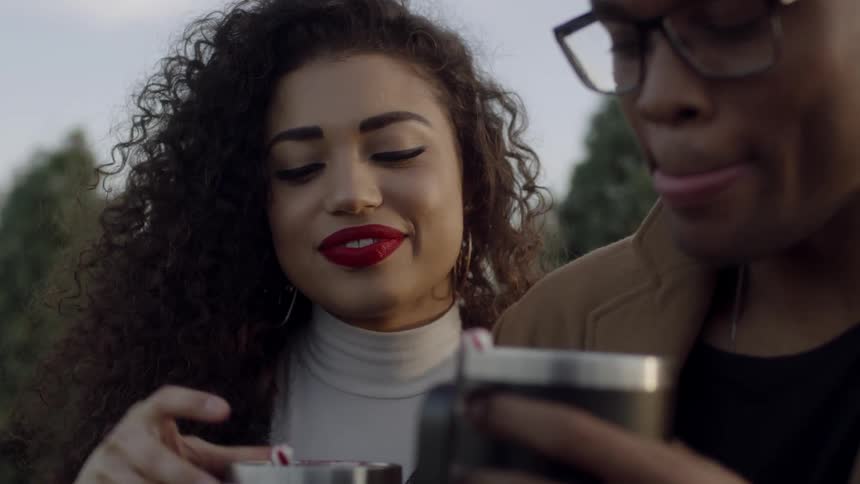 Man and woman drink hot chocolate on a tree farm