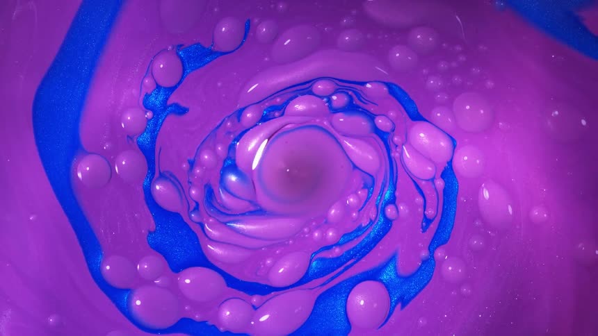 Purple liquid is spun and joined by vibrant blue liquid