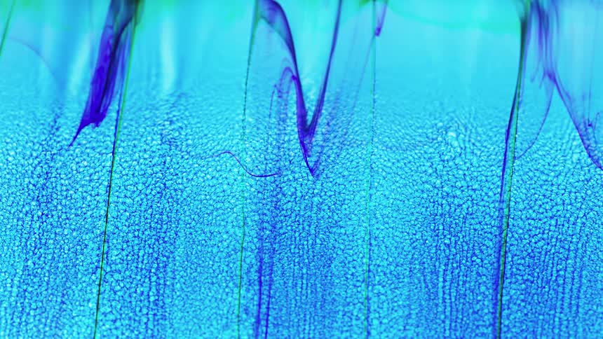 Blue and green liquid drips slowly in streaks