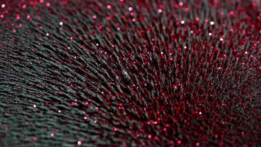 Magnetic spikes of iron fillings are moving with red glitter and create a powerful bokeh
