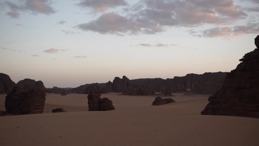 Rocks scattered throughout sand in a desert at sunset