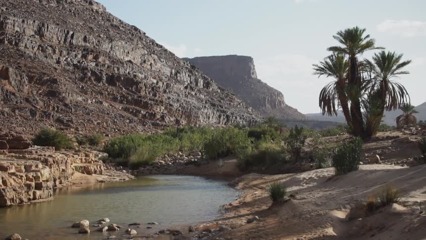 A small pond sits by a rock mountain