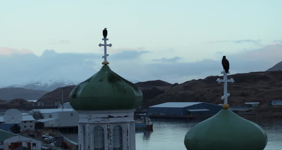 Eagles are perching on crosses atop a church at dusk