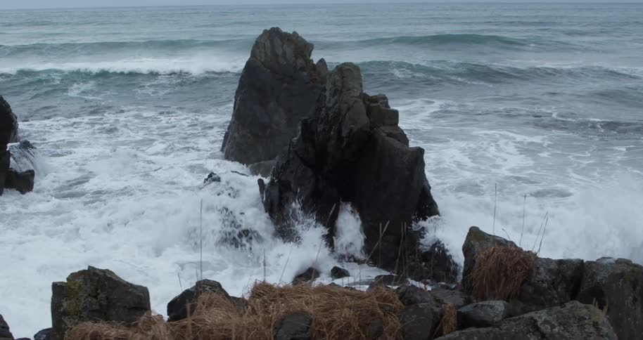 Waves are crashing over rocks on at the beach during the day