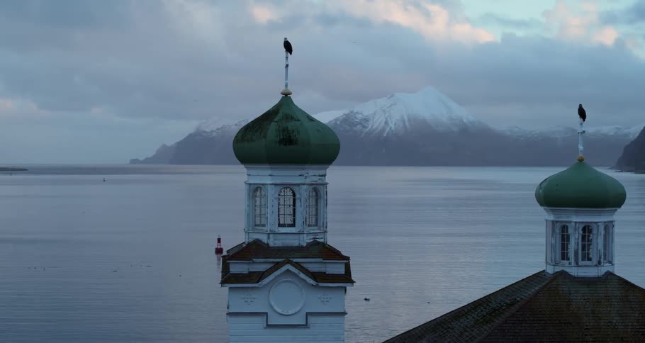 A bald eagle sits on a steeple overlooking the harbor