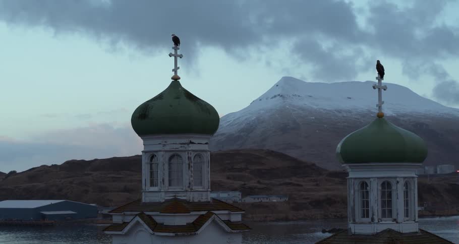 Eagles are perching on crosses atop a church at dusk