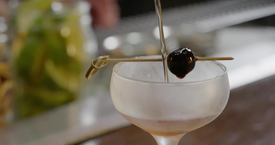 A drink is poured into a cocktail glass