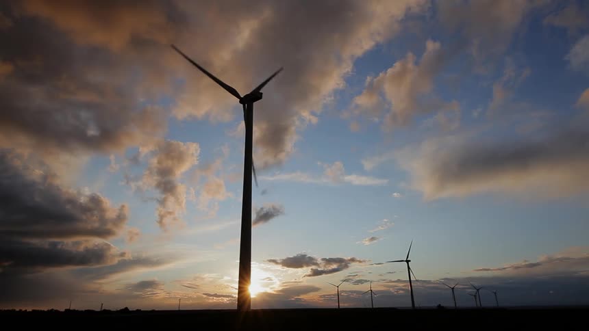 Clouds float above wind turbines at sunset