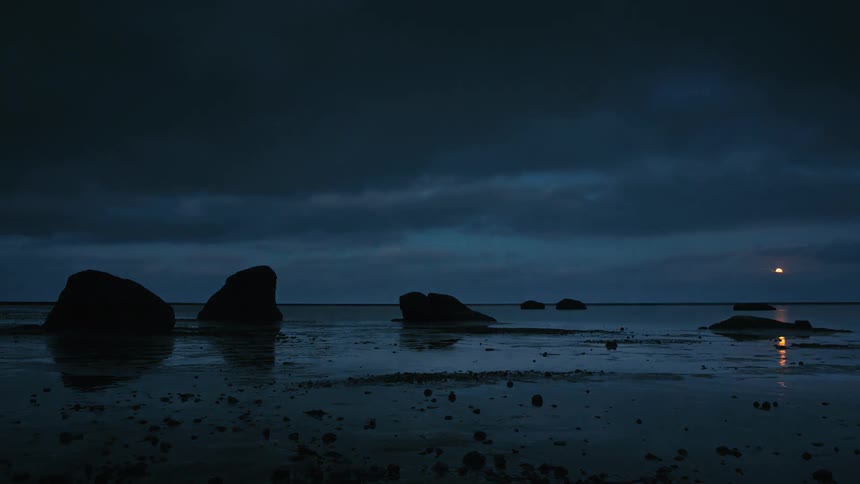 Clouds float over an ocean shore at sunset
