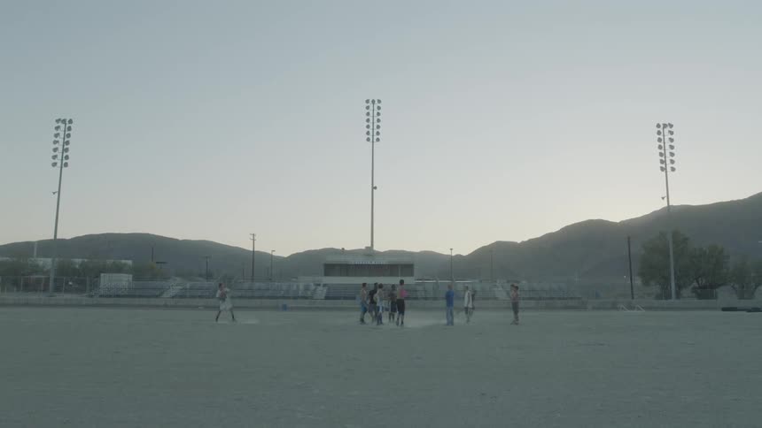 Guys play football on a football field in the evening