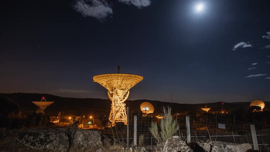 Clouds drift over an observatory at night