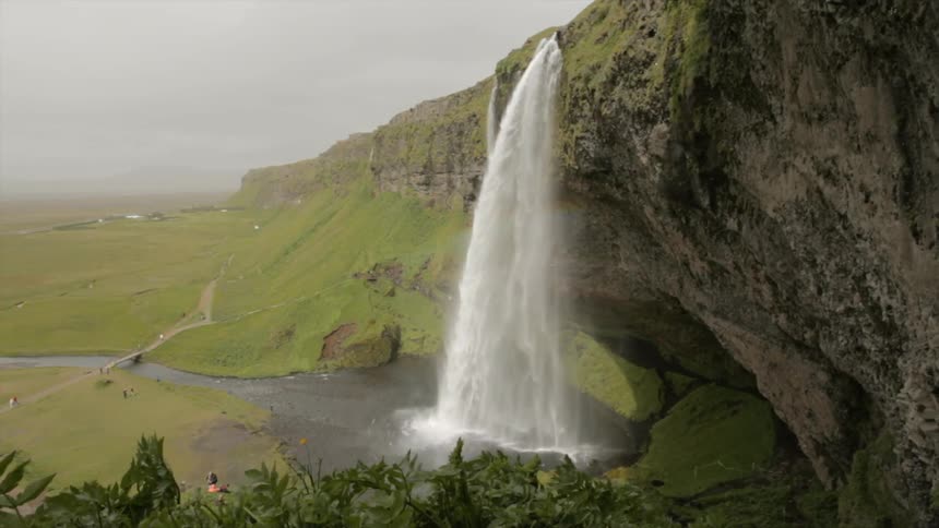 Water falls off the side of a stone cliff