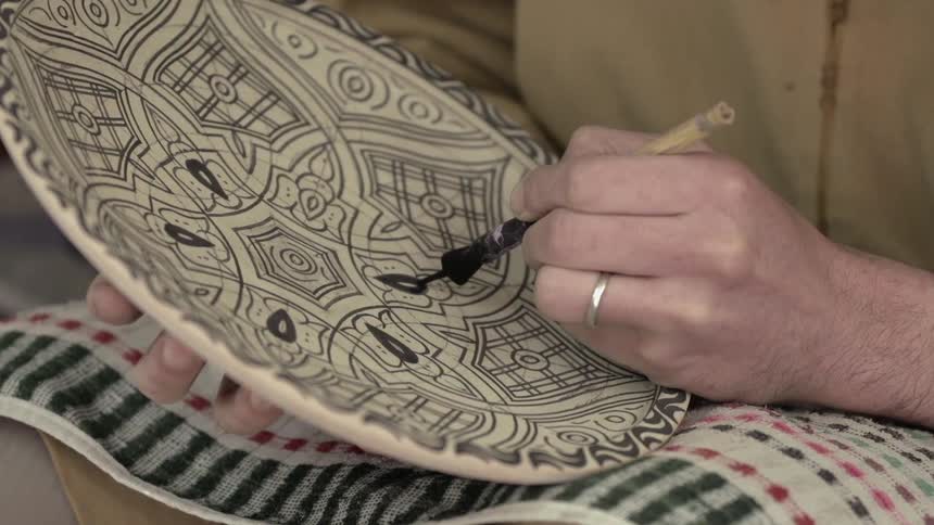 A man paints a plate