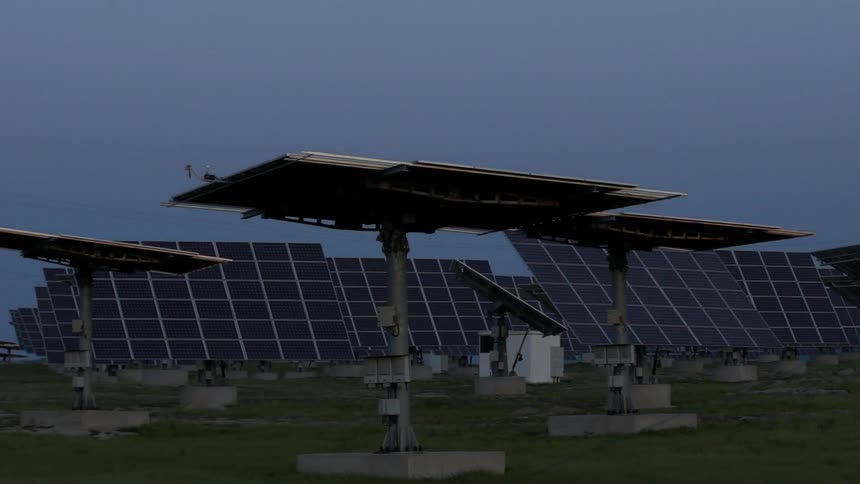 Solar panels rotate in a field at sunrise
