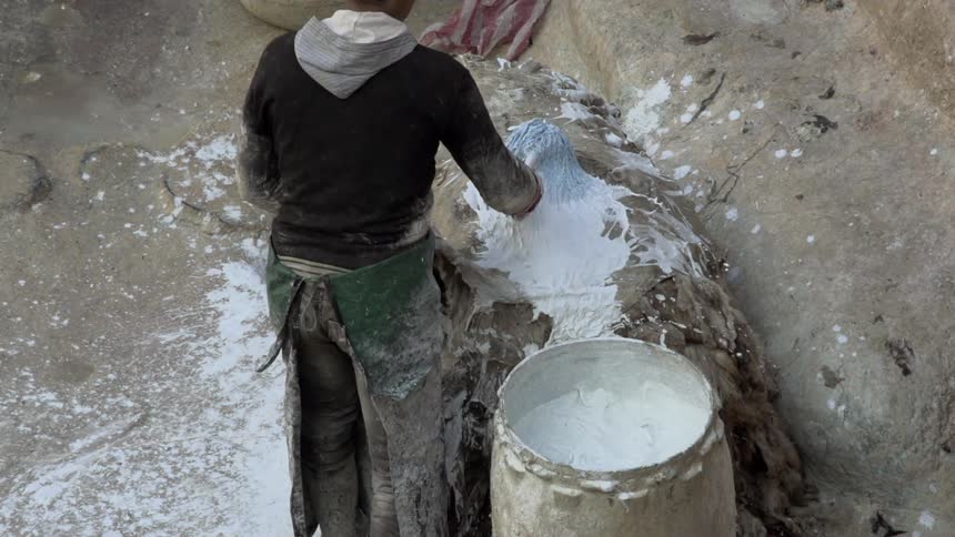 A man splashes white paint on fabric using a brush