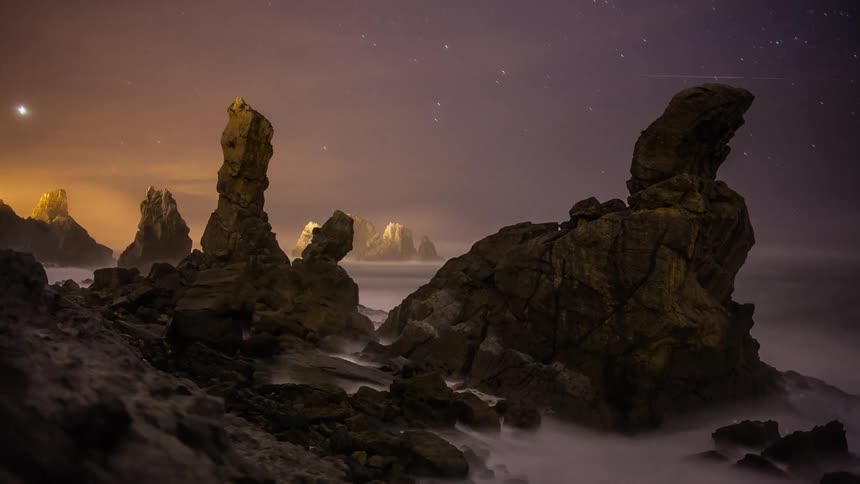 Mist floats around rock formations at night
