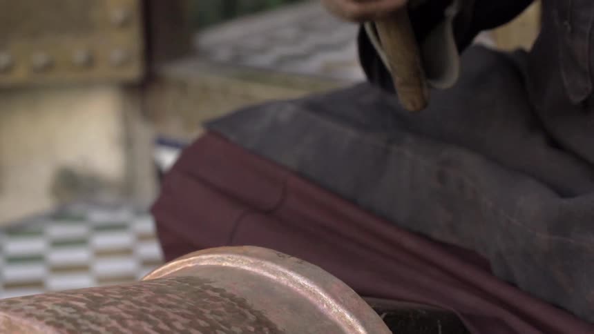 A person hammers a piece of metal