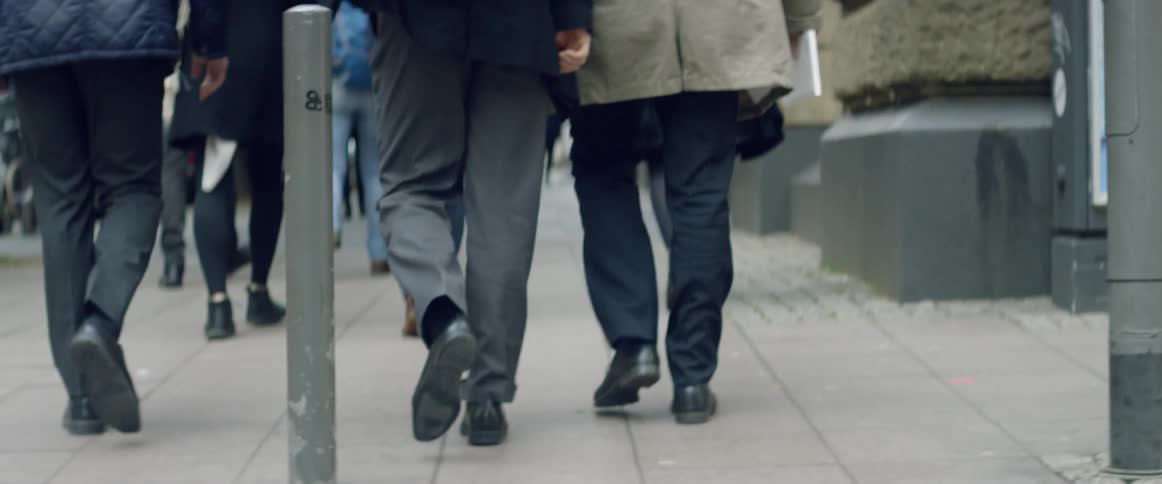 People cross a city street then walk on the sidewalk