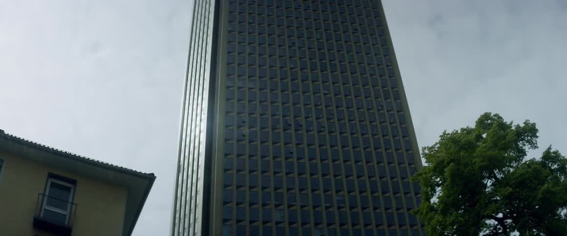 A car drives beneath a towering skyscraper