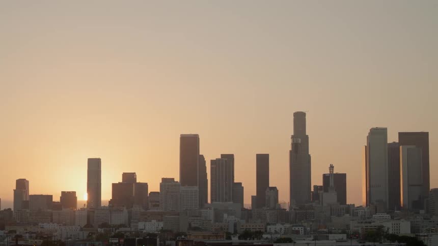 The sun sits on the horizon behind the city skyline