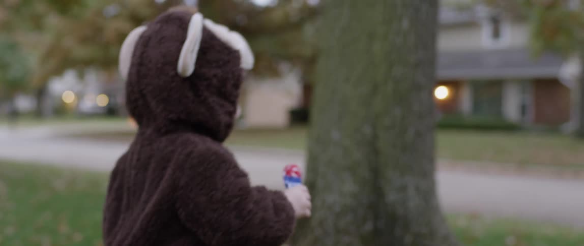 A toddler wears a costume while holding a sucker on halloween