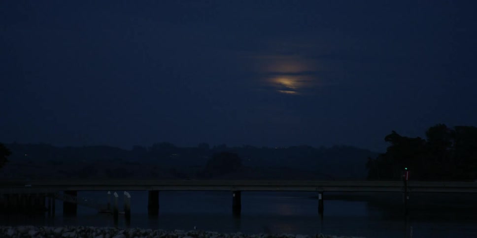 A car drives beneath a glowing moon