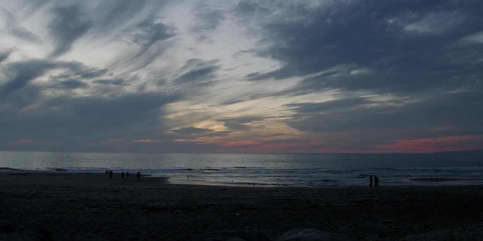 People walk on the beach at sunset