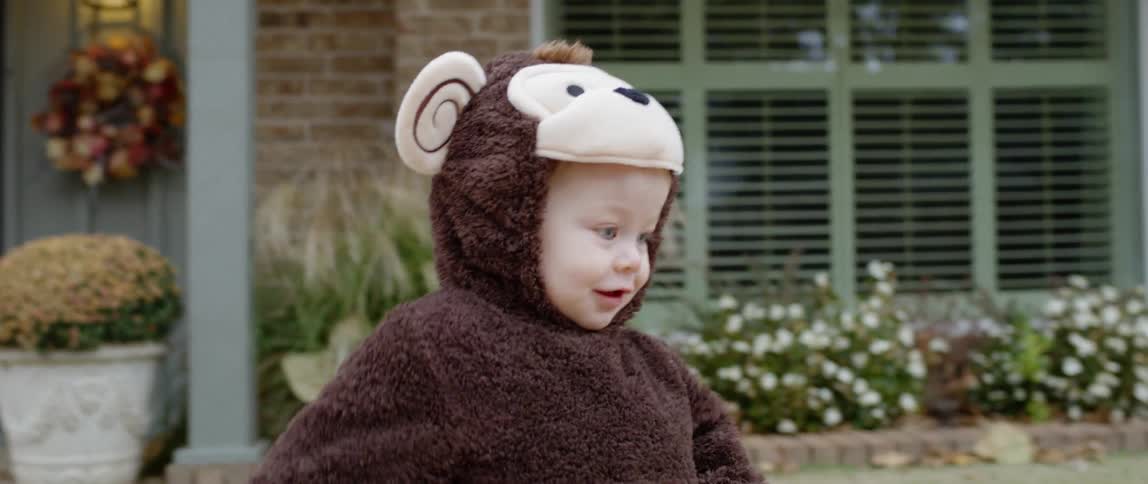 Child in a costume walks through a front yard