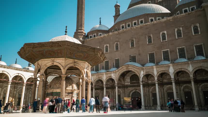 People are walking through the plaza of the mosque of muhammad ali on a sunny day
