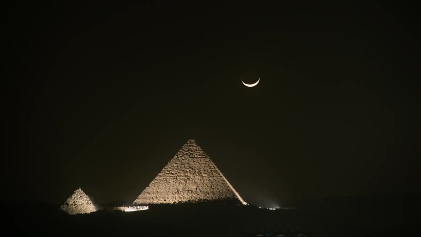 The moon sets behind the pyramid
