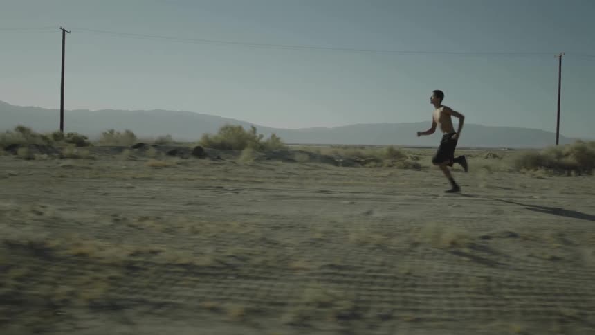 Man running across a dirty path on a cloudy day