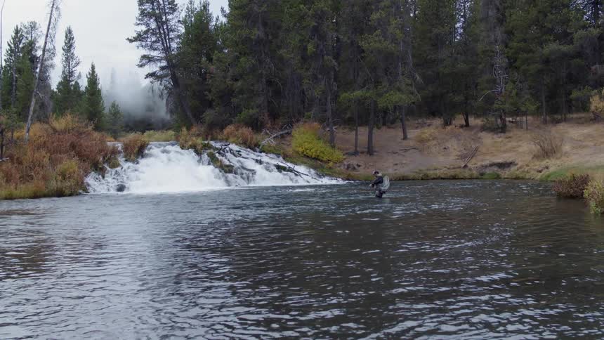 A man fly fishes in a stream