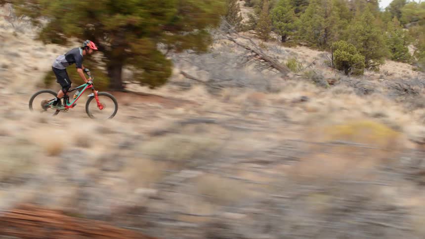 A man rides a bicycle along a mountain trail