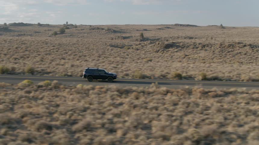 Jeep drives on a country road surrounded by plains