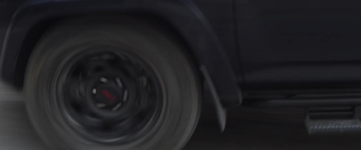 A vehicle is bouncing as it drives over a dirt road during the day