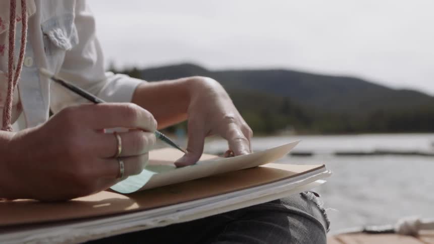 An artist paints on a lake dock