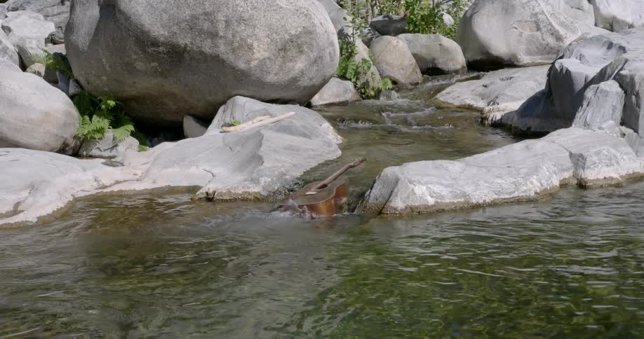 Guitar floats down a rocky stream