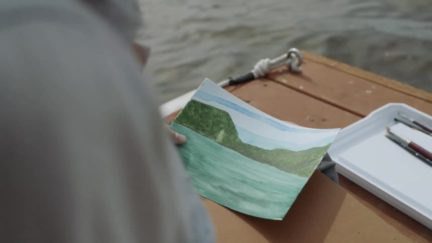 An artist paints a lake from a dock