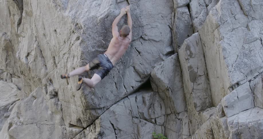 Man climbs up a side of a cliff