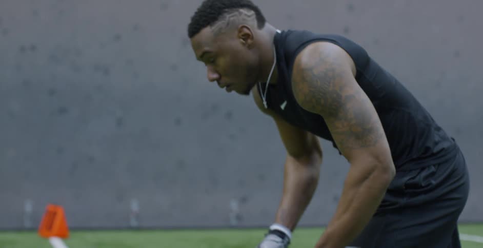 A male athlete is setting into position as he trains on an indoor football field