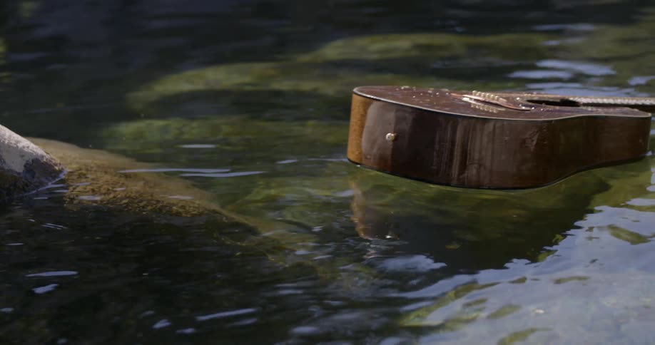 A guitar floats down a flowing stream