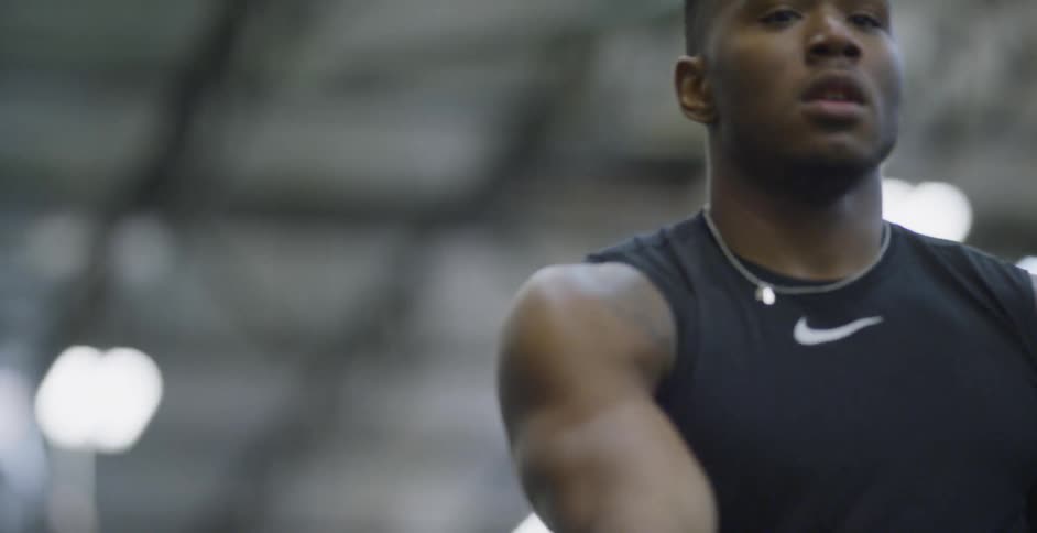 A male athlete is tossing a football as he trains indoors