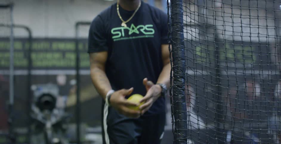 A man throws a softball in a batting cage