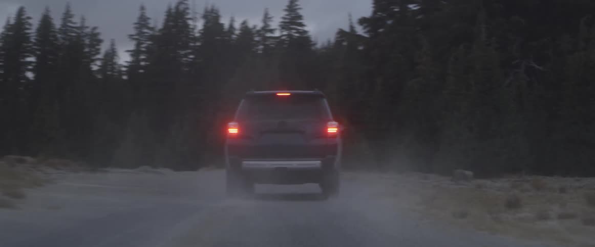 A vehicle drives on a dirt forest road