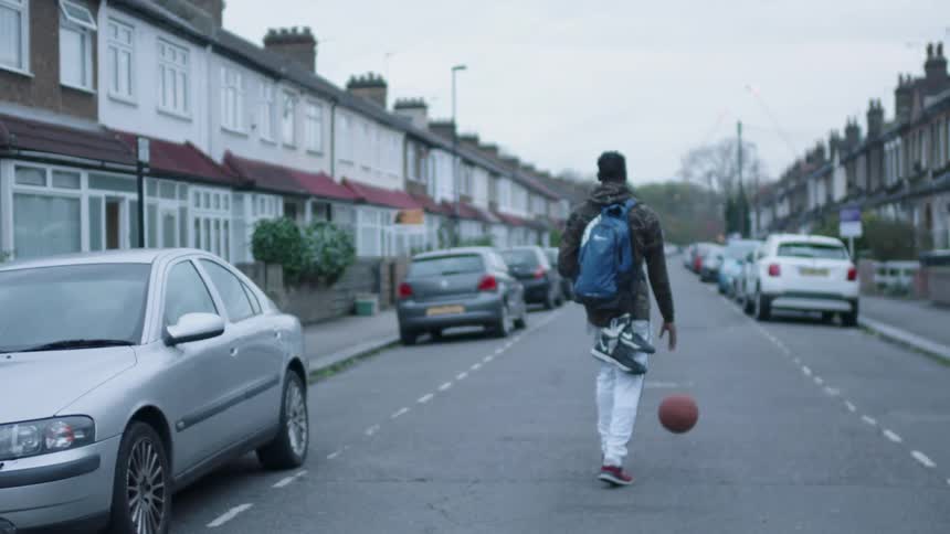 A man bounces a basketball on a city street